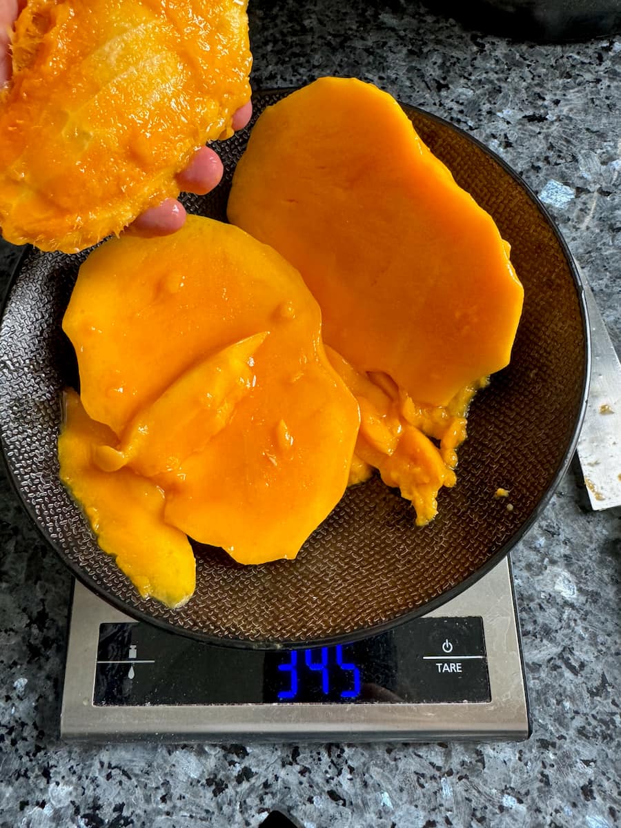 sweetest orange mango sliced, showing on a scale that it weighs 345 grams.