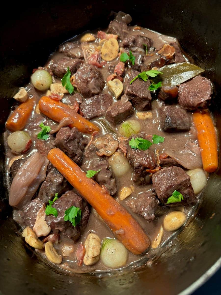 crock pot of Boeuf Bourguignon with carrots, mushrooms and pearl onions, topped with parsley