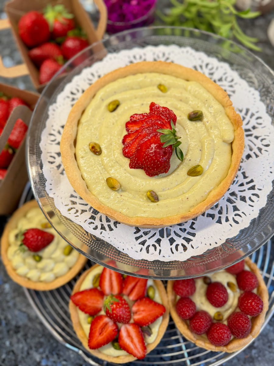 one large French tart with pistachio pastry cream and strawberries and 3 mini tartlets