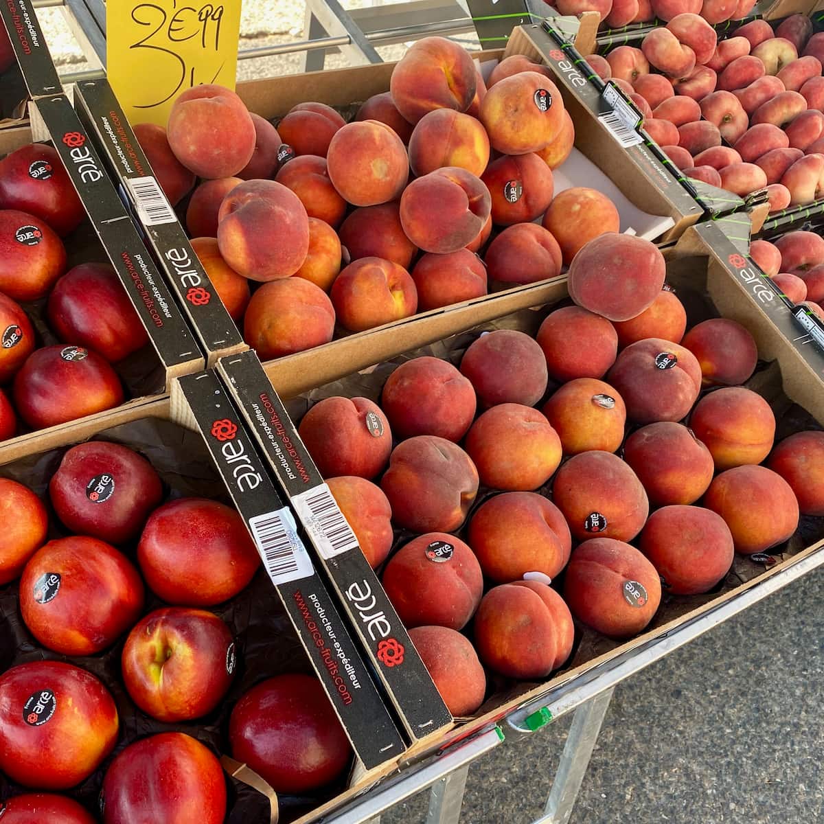 crates of fresh peaches, doughnut peaches and nectarines at a French market