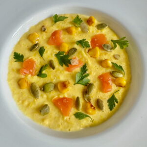 sweet corn soup restaurant style like in Paris - a creamy chowder topped with herb leaves, pumpkin seeds, smoked salmon and fried corn