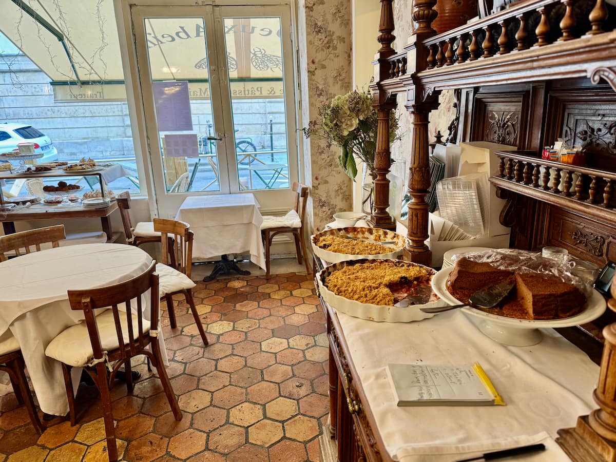 cosy Paris tearoom with honeycomb floor tiles and dishes of crumble on the counter