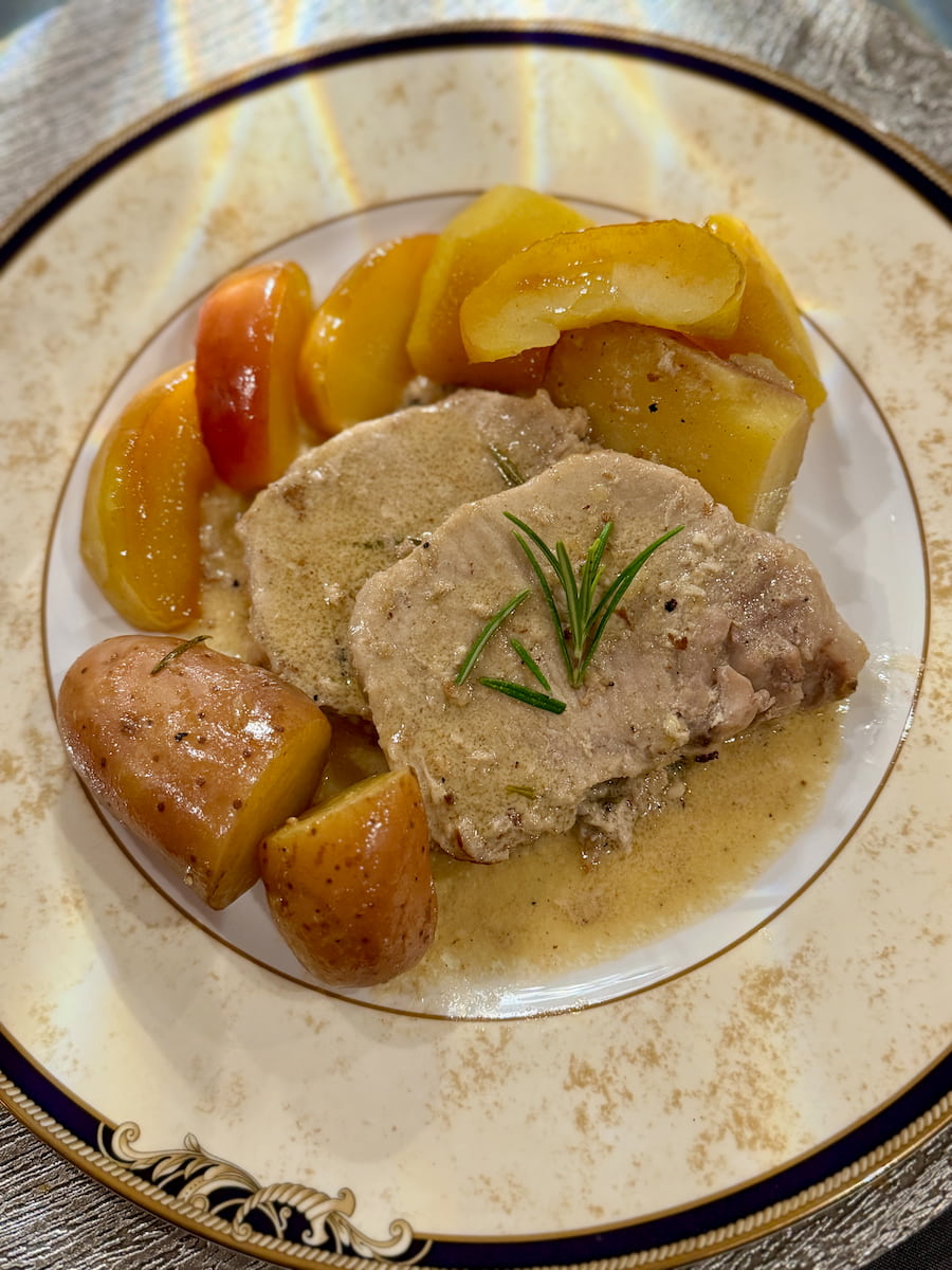 slices of tender pork roast in apple cider sauce surrounded with chopped potatoes and apples