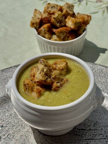homemade croutons made with garlic and French bread topping for a pea soup next to a ramekin of more croutons
