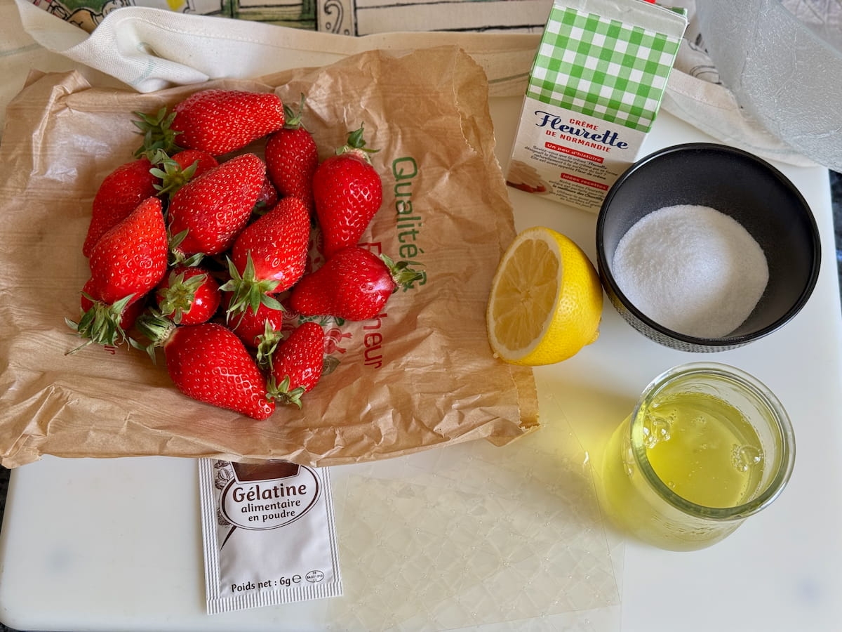 ingredients laid out to make a French strawberry mousse - with strawberries, sugar, egg whites, sugar, cream and gelatine - either powder or sheets