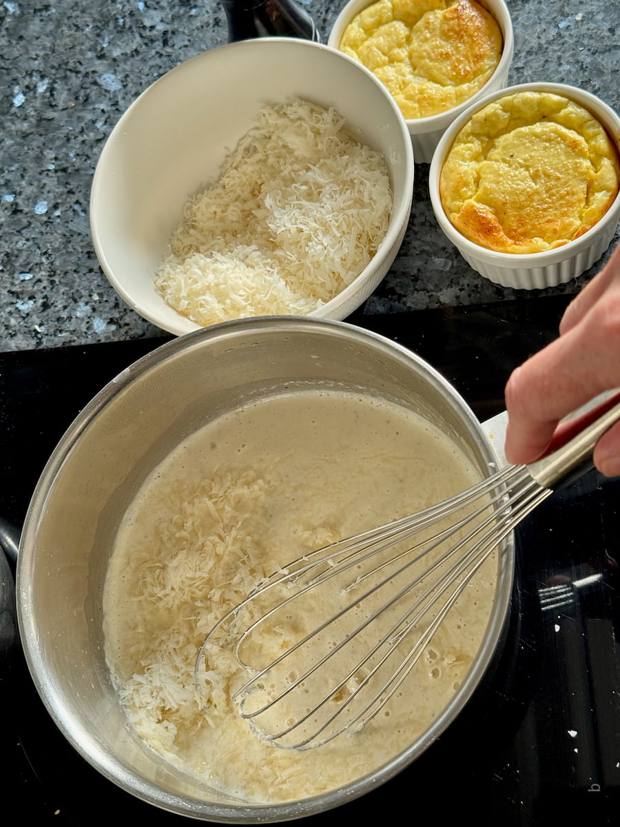 whisking grated parmesan cheese into hot cream to make a sauce