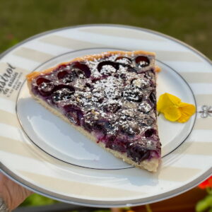 slice of French blueberry tart, baked in the oven with a crisp pâte sucrée pastry and dusted with powdered sugar
