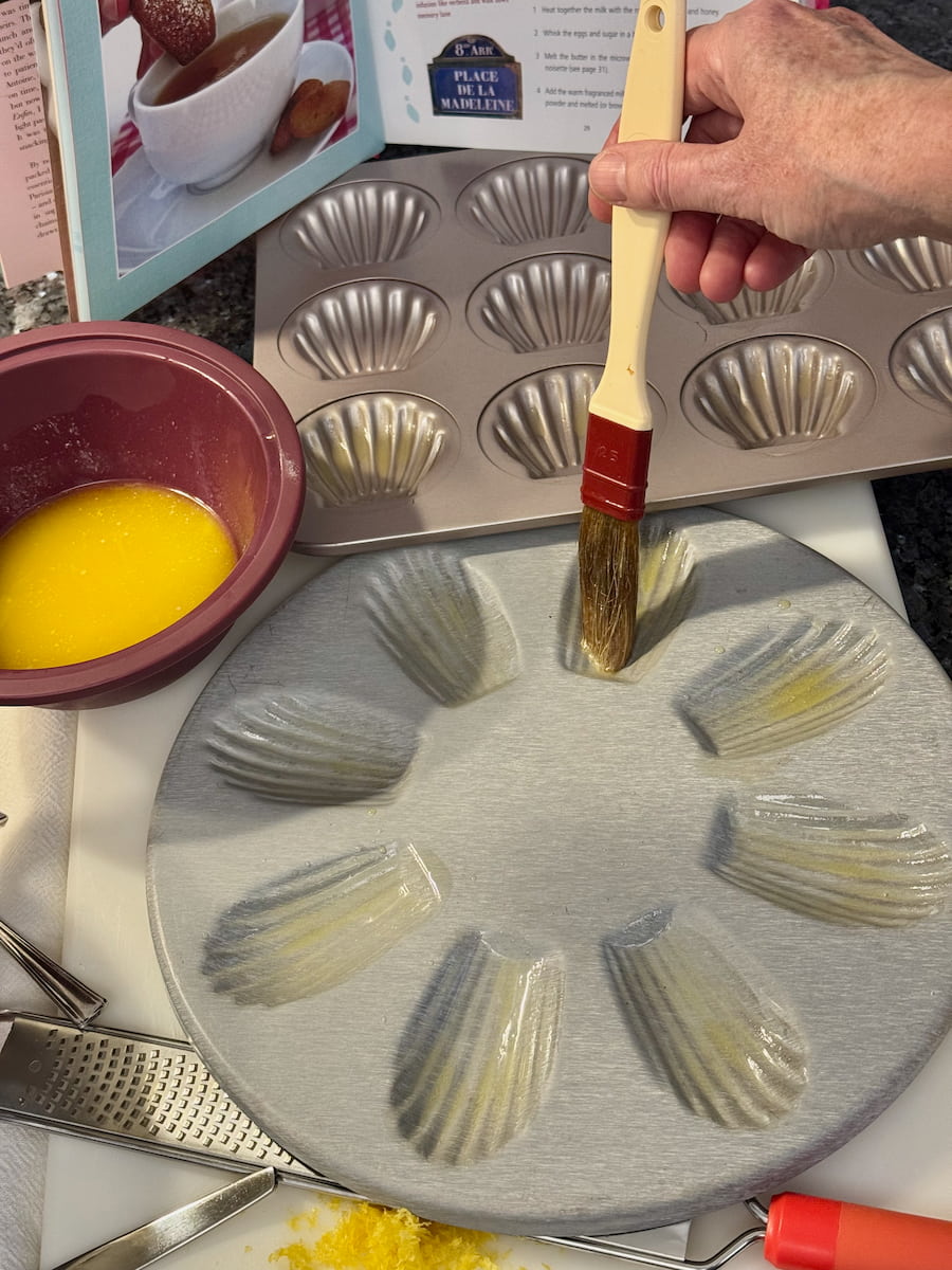 buttering a classic French Madeleine tin with a brush