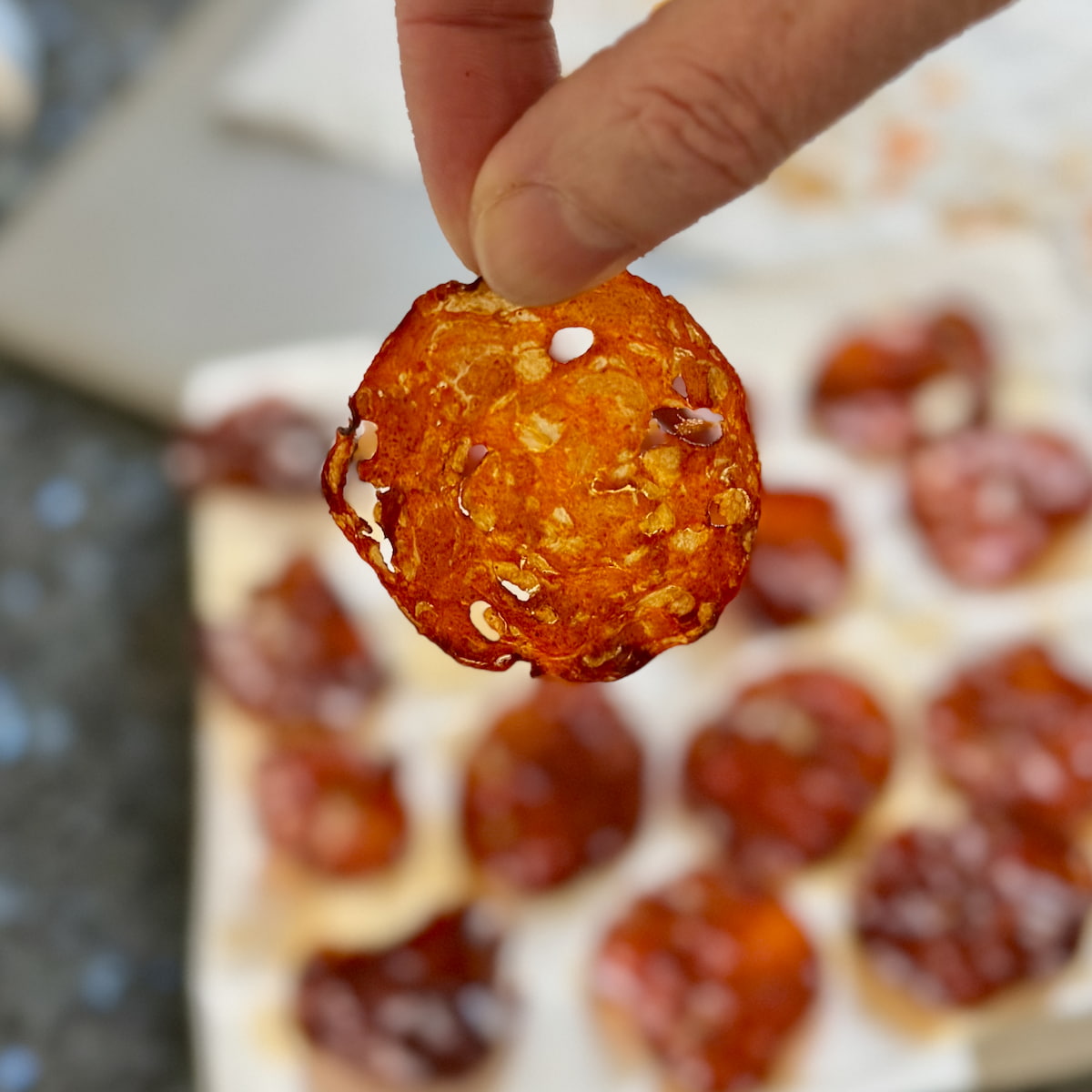 holding a wafer thin crispy slice of chorizo against the light
