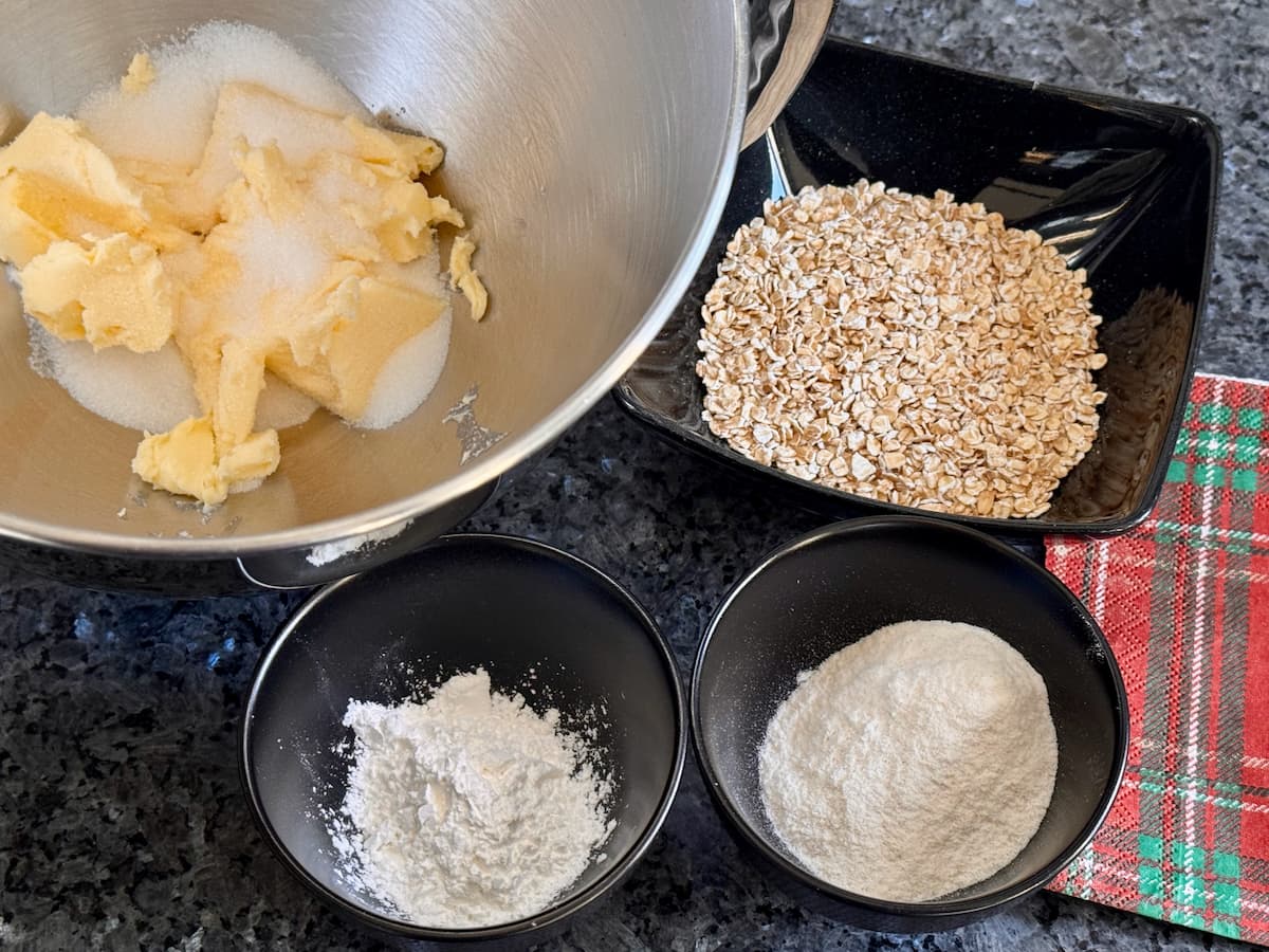 butter, sugar and salt in a bowl of a stand mixer with bowls of oats, rice flour and cornflour to make gluten free shortbread 