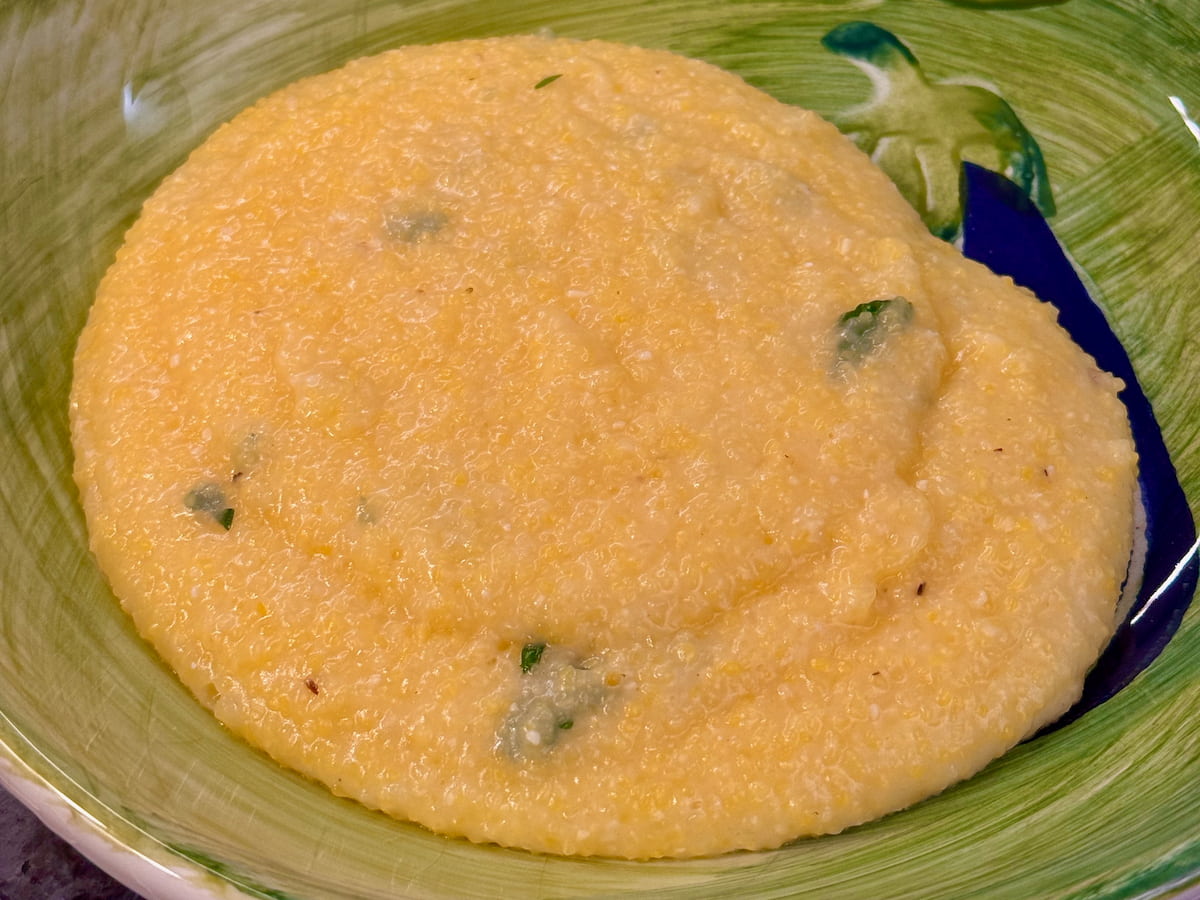 bowl of plain corn polenta, looking creamy and glossy with cheese, butter and parsley