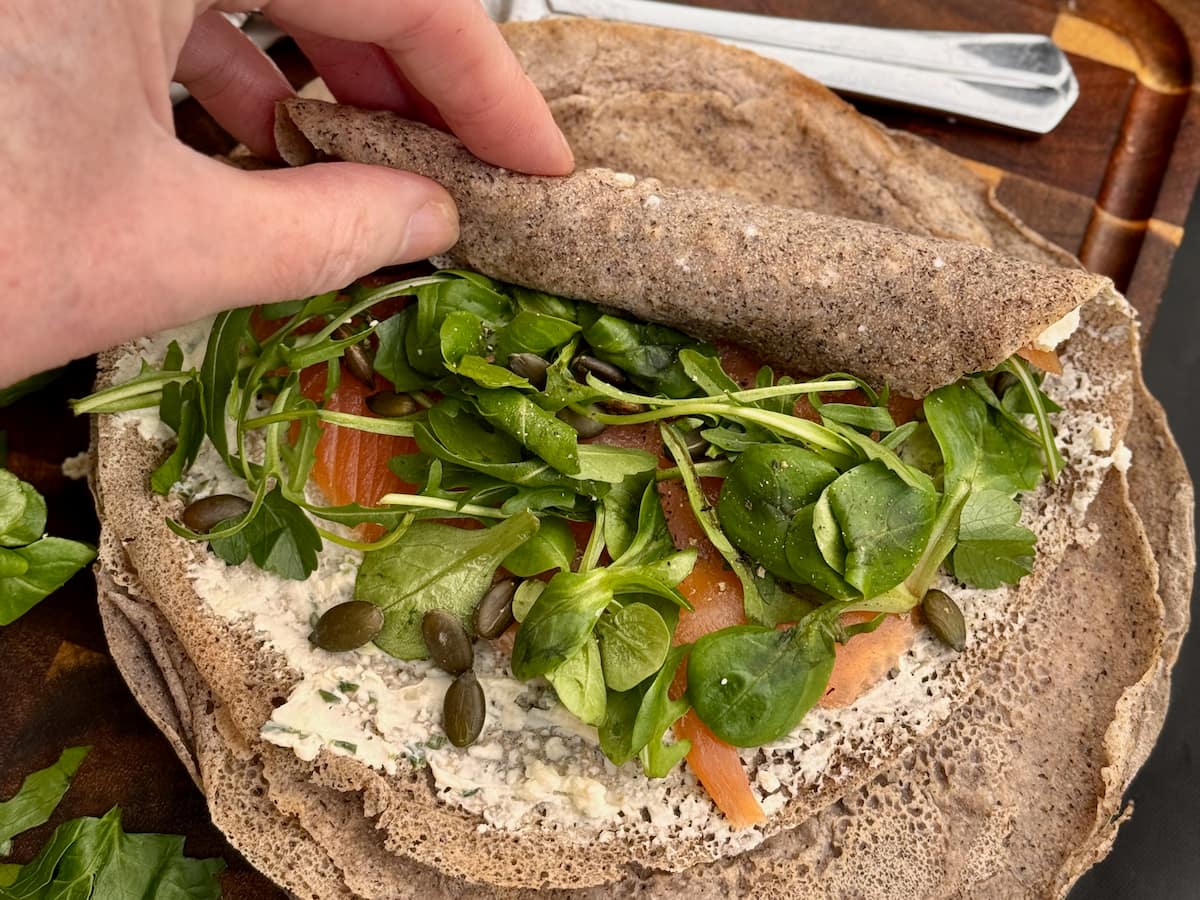 tightly rolling a buckwheat wrap so that the filling stays intact