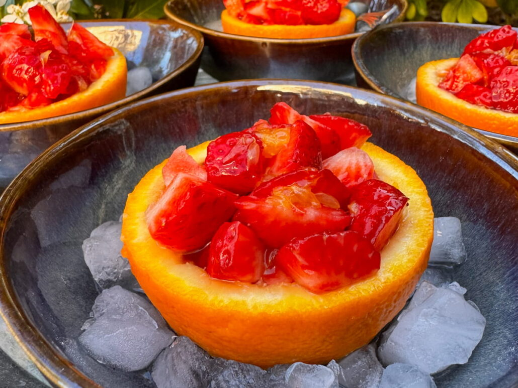 scooped out orange halves with strawberry salad served in bowls of crushed ice