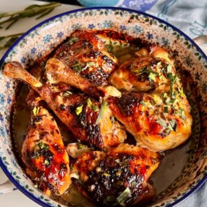 Lemon chicken thighs baked with garlic, herbs and fresh lemon in a rustic French baking dish