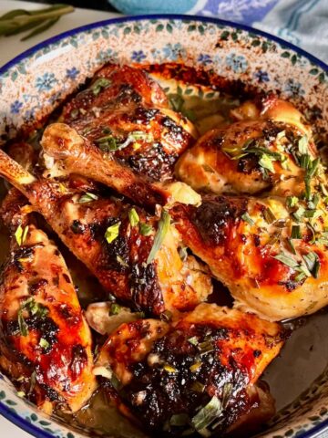 Lemon chicken thighs baked with garlic, herbs and fresh lemon in a rustic French baking dish