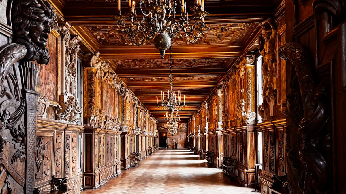 The main gallery inside the Château de Fontainebleau with wood panelling and sculptures and no tourists