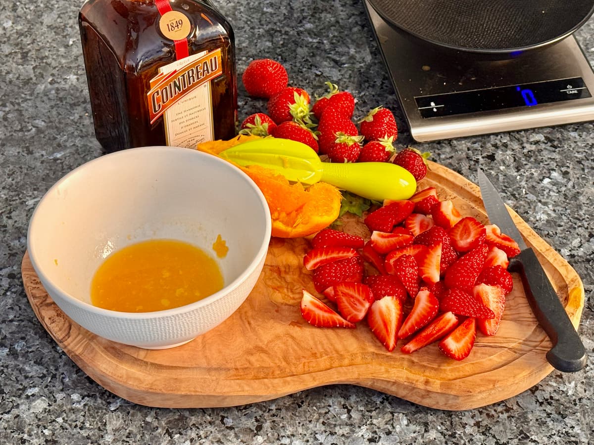 cut fresh strawberries, a bowl of freshly squeezed orange juice, Cointreau with cream chilling in the fridge
