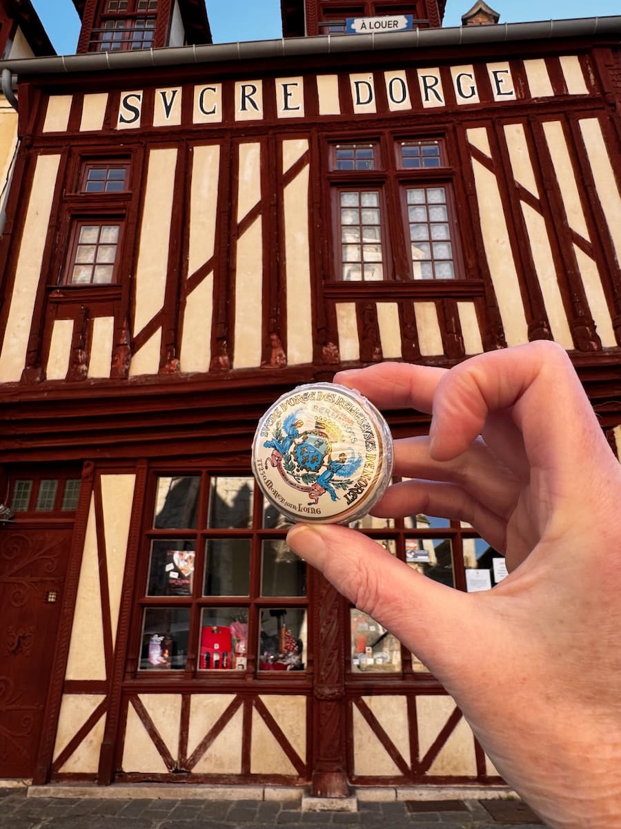 holding a sweet box of barley sugars in front of an old timbered house in Moret-sur-Loing