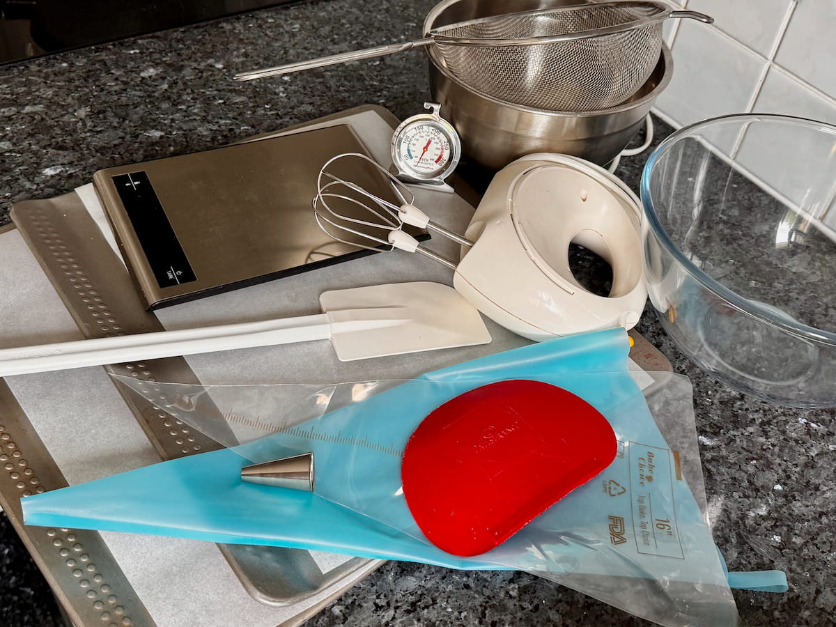 essential equipment to make macarons: digital scales, electric whisk, 2 bowls, spatula, sieve, lined flat baking trays, piping bag and a plain tip
