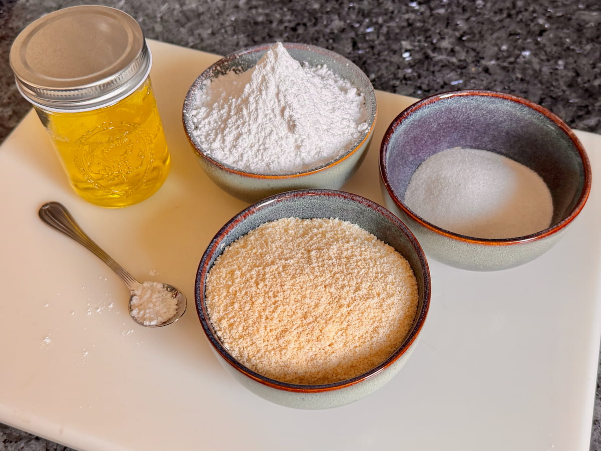 basic macaron ingredients of fine unblanched almond flour, egg whites, powdered and superfine sugar all weighed in bowls