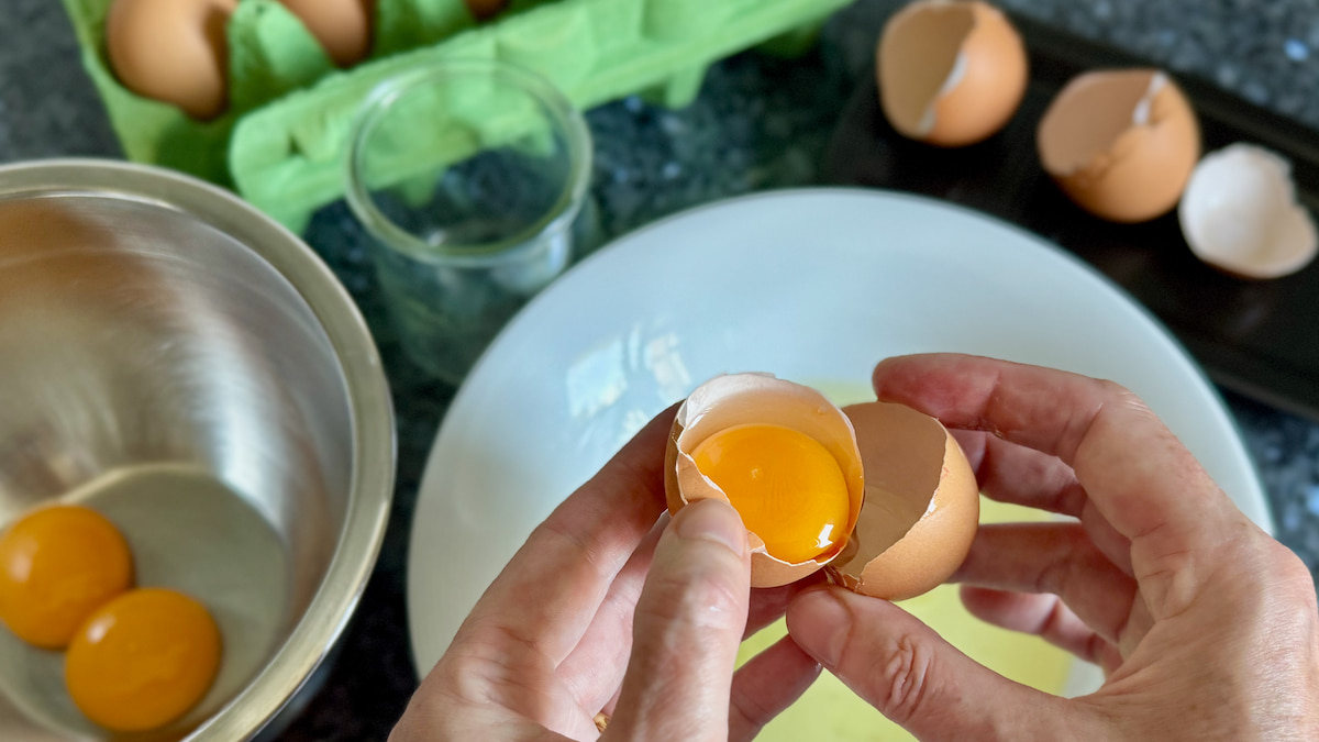 separating eggs shell to shell leaving only the egg yolks and whites in a bowl underneath